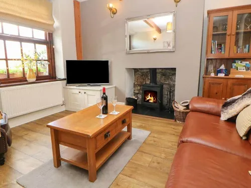 Cottage lounge with leather sofa and woodburner fireplace