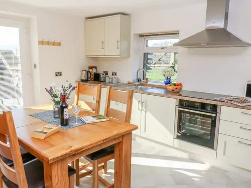 Cottage kitchen with dining table, oven and sink under window