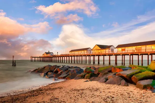 Sunrise illuminating the Southwold Pier and gentle waves on the Suffolk coast.