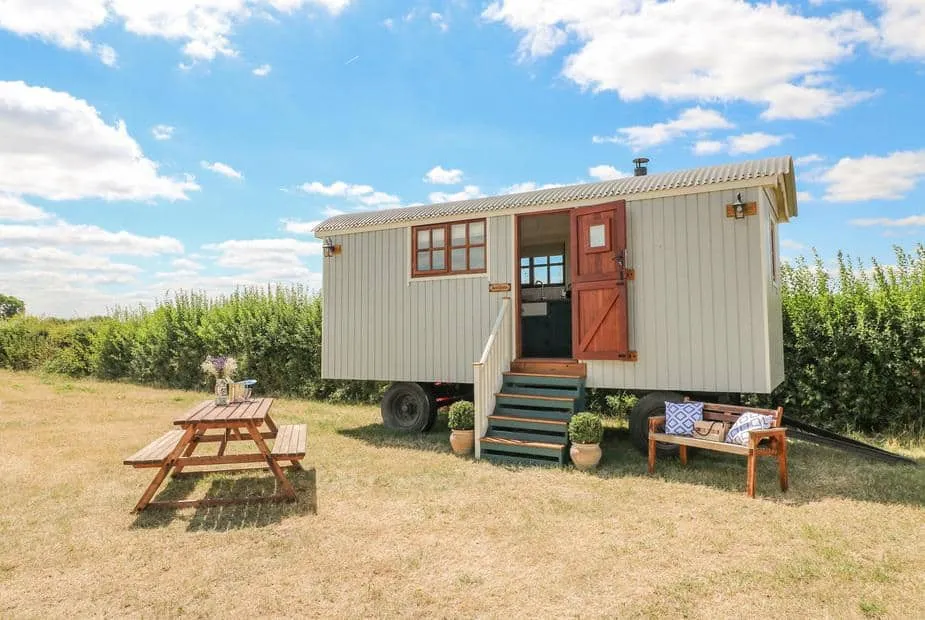 Sweet Caroline Shepherd’s Hut with outdoor bench and picnic table on grassy field