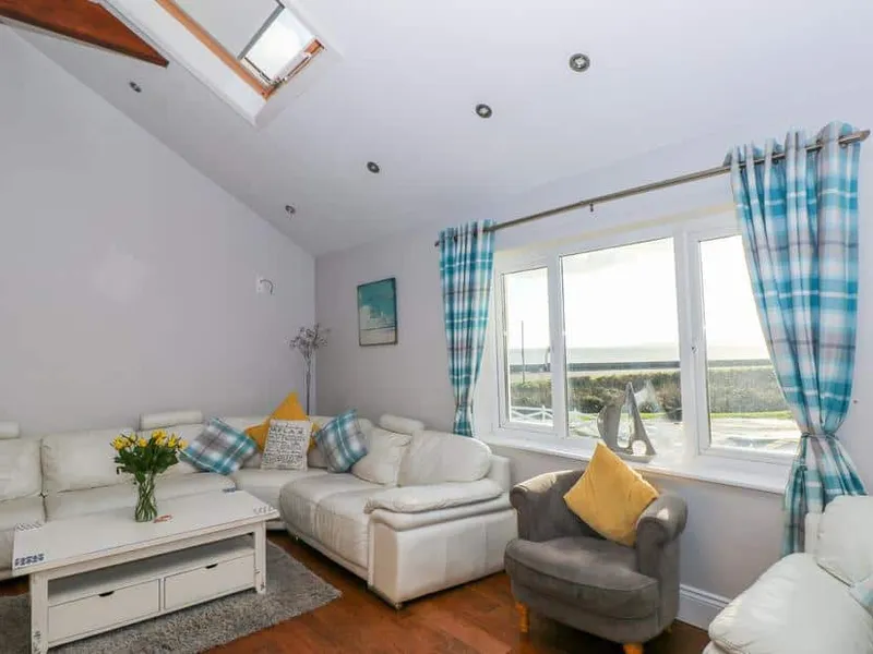 Swn y mor lounge with white sofas, skylight, and large window showing sea views