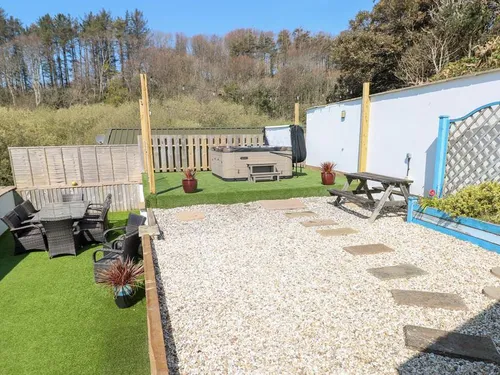 Cottage garden with gravel path, patio seating and hot tub