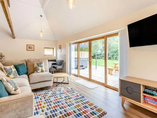 Living room with L-shaped sofa, patio doors, and garden view
