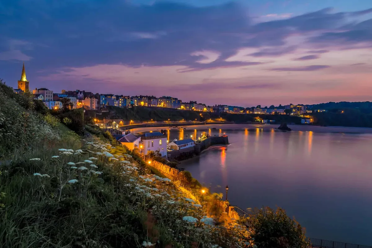 Tenby's harbour and town glowing with warm lights during a peaceful blue hour after sunset