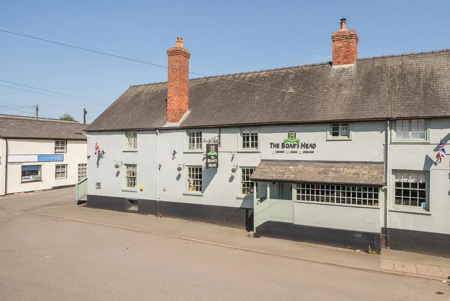 The Boars Head Pub exterior with sign and two red brick chimneys