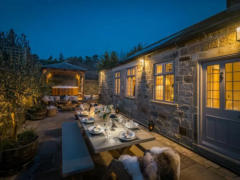 The Brew House stone exterior with outdoor dining area and covered hot tub at dusk.