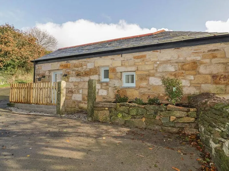 The Bull Pen stone cottage exterior with slate roof and low stone wall in front.