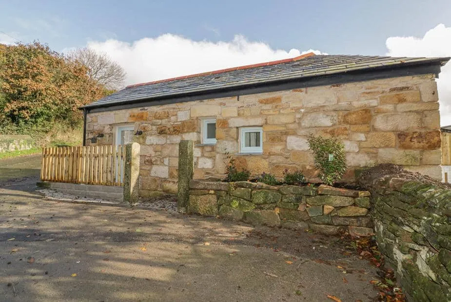 The Bull Pen stone cottage exterior with slate roof and low stone wall in front.