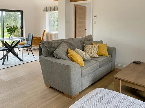 Cottage lounge with grey sofa and dining table by sliding glass doors