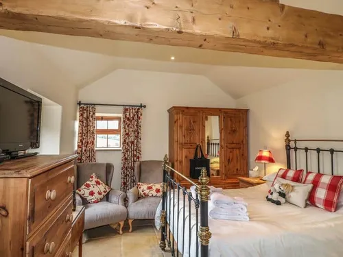 Cottage bedroom with iron bed, wooden wardrobe, and chest of drawers
