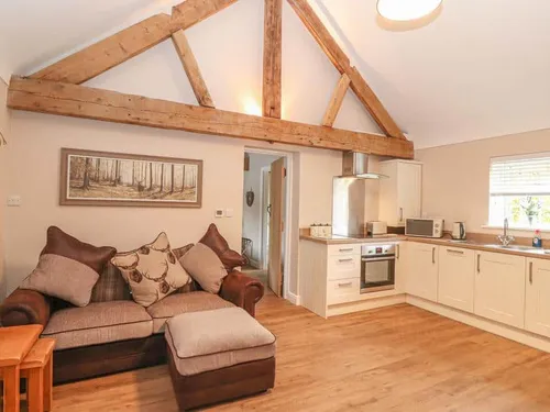 Cottage open-plan lounge and kitchen with exposed wooden beam and sofa