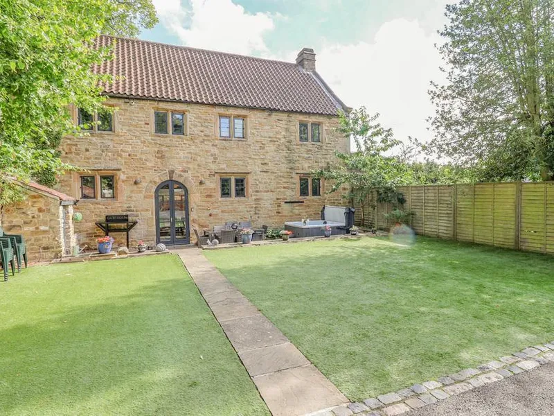 The Gatehouse stone cottage exterior with private lawn and hot tub.