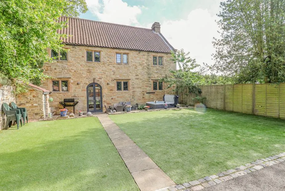 The Gatehouse stone cottage exterior with private lawn and hot tub.