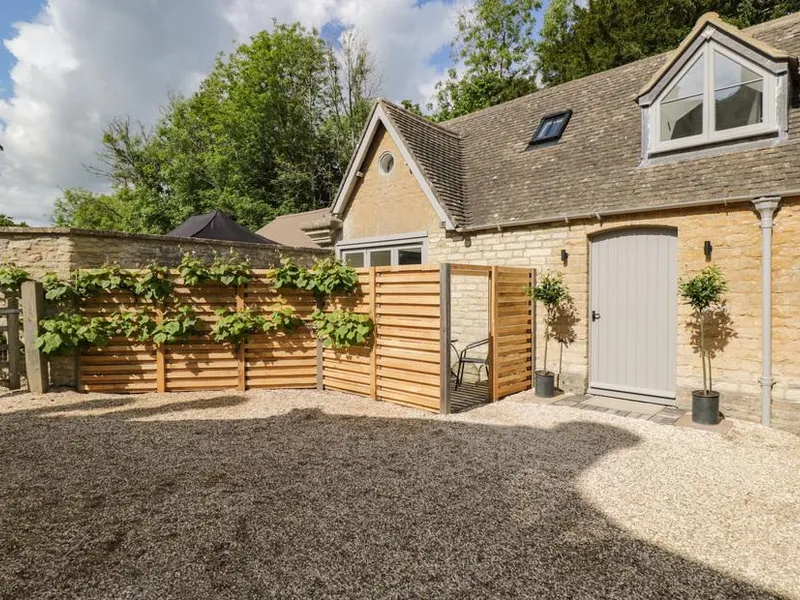 The Hayloft with gravel courtyard and timber privacy screens with climbing plants