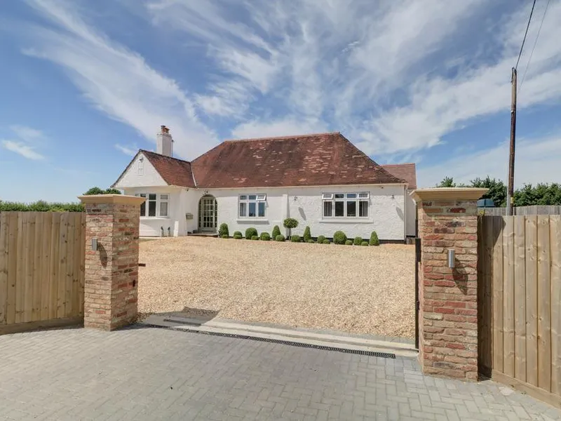 The Little Paddock with red tiled roof, gravel driveway and wooden gated entrance