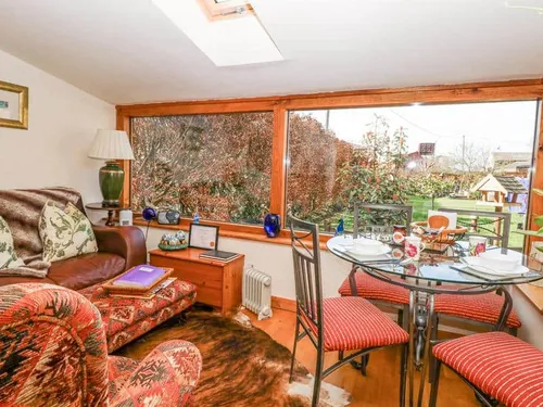 Lodge living area with glass dining table and large windows overlooking garden