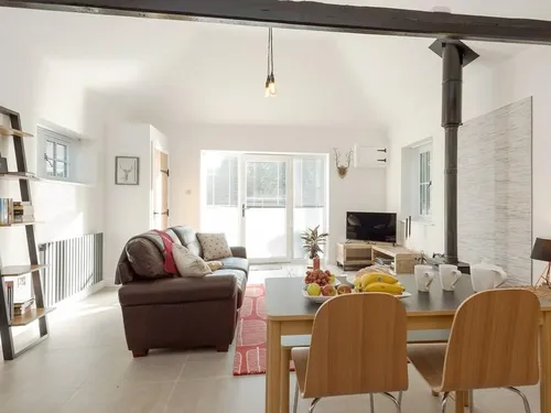 Cottage living area with woodburner, dining table and sofa facing TV