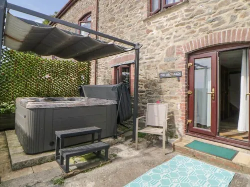 Cottage patio with hot tub and seating by double doors