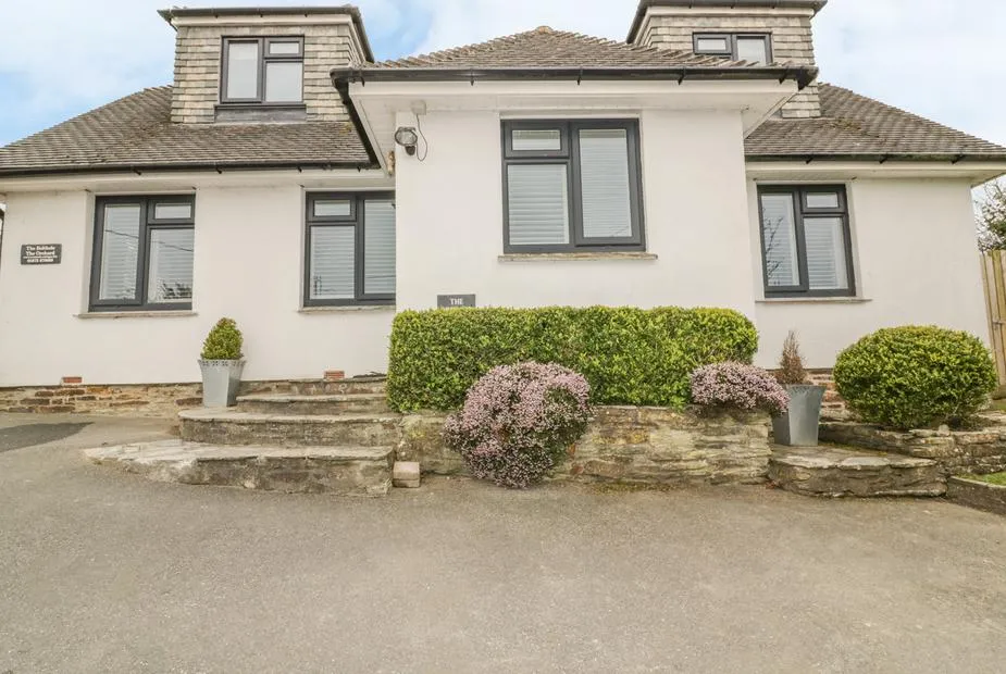 The Orchard cottage exterior with stone steps and trimmed hedges at the entrance.