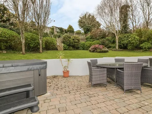 Cottage patio with hot tub, outdoor dining set and view of lawn with trees