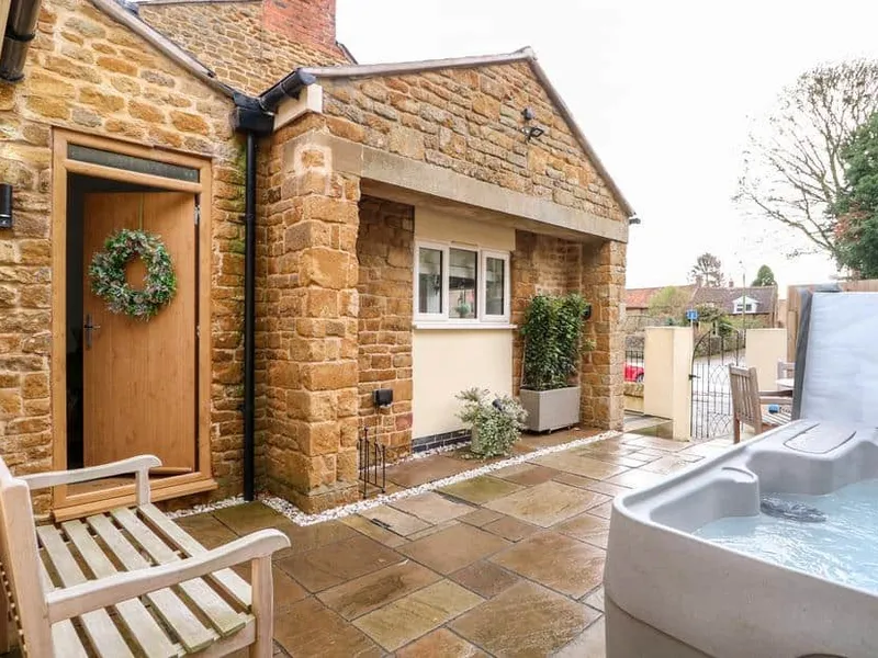 The Pinfold stone exterior with hot tub on a paved patio