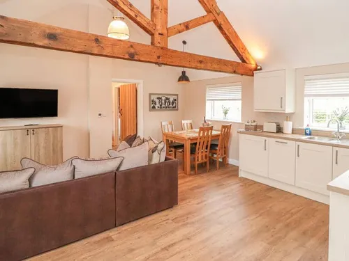 Cottage open-plan living area with sofa, dining table, kitchen and exposed wooden beams