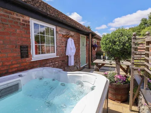 Cottage patio with hot tub, bench seating and potted plants