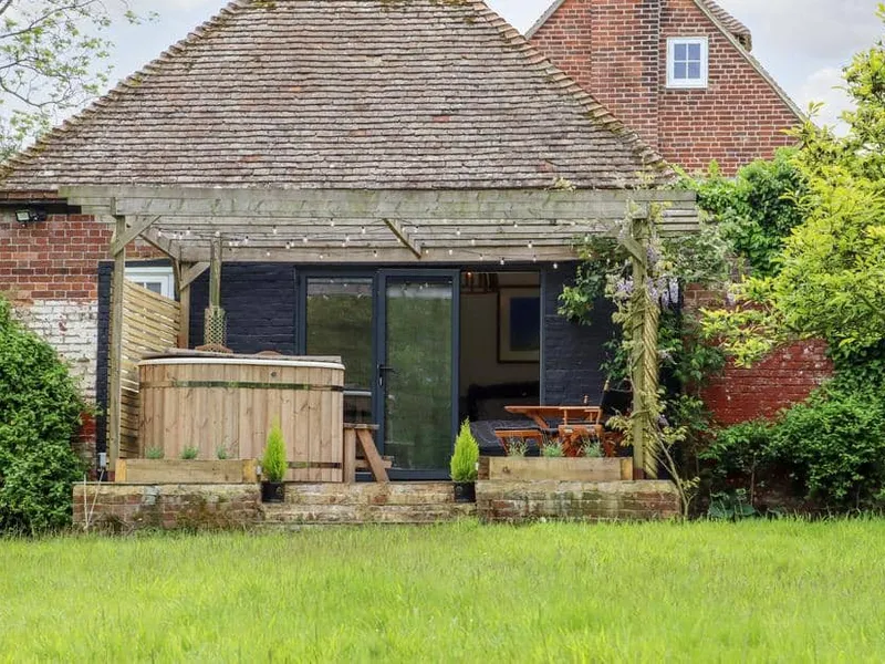 The Snug exterior with wooden hot tub and pergola in garden.
