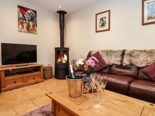 Cottage lounge with log burner, leather sofa and TV