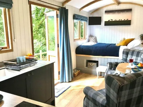 Lodge interior with kitchenette, bed and small dining table by open door