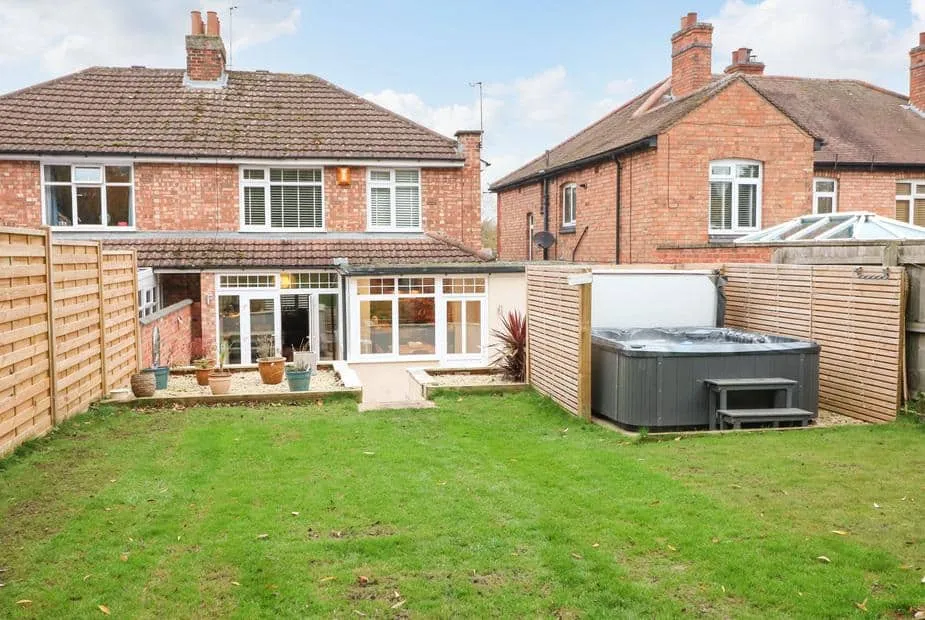 The Willows rear garden with patio, potted plants and private hot tub.