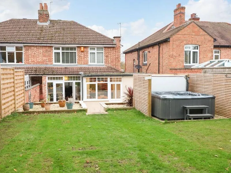 The Willows rear garden with patio, potted plants and private hot tub.