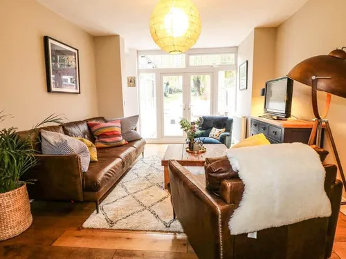 Cottage living room with leather sofas, rug, and French doors to garden