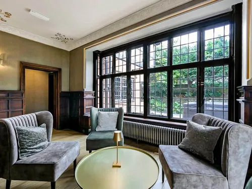 Cottage sitting area with three chairs and large leaded window