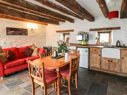Kitchen and living area with wooden beams and red sofa