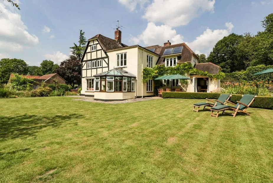 Valley House with conservatory and deck chairs on a large lawn garden