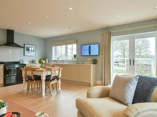 Cottage kitchen and dining area with table, chairs and French doors to garden