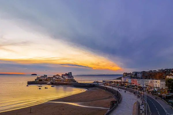 Aerial view of Weston-super-Mare at sunset, showing the sweeping sandy beach, the town seafront, and a dramatic golden horizon.