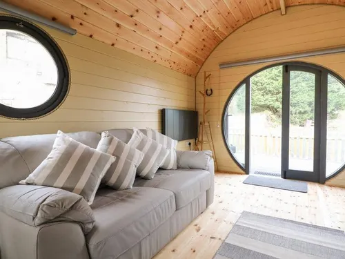 Lodge lounge with grey sofa and circular glass doors to outside deck