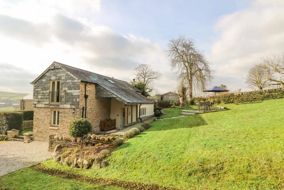 Woodfield Coach House with stone exterior and outdoor seating area on a large lawn