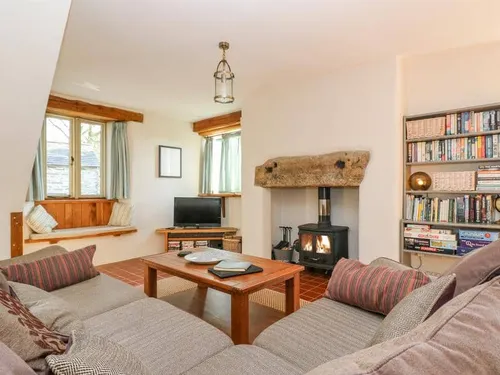 Cottage lounge with wood-burning stove, bookshelves and window seat