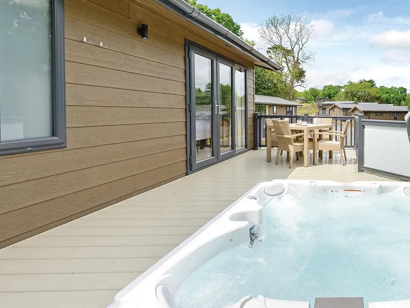 Yaverland Premier lodge deck with outdoor hot tub and dining table overlooking nearby lodges