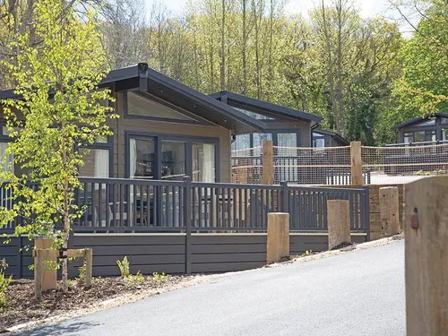 Lodge with decked veranda and railings surrounded by trees